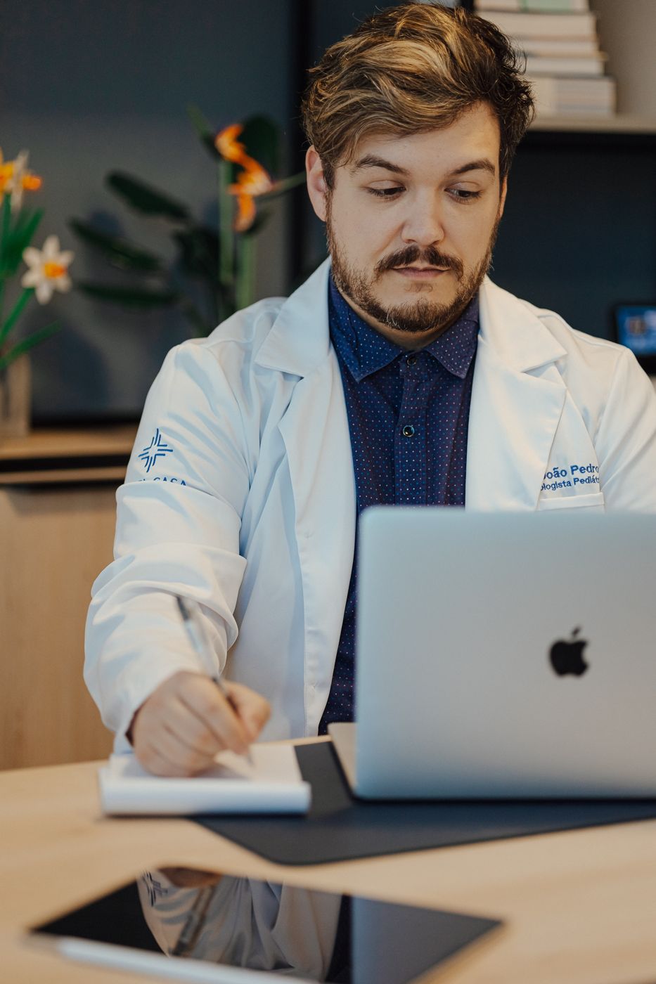Dr. João Pedro, de jaleco, fazendo anotações
