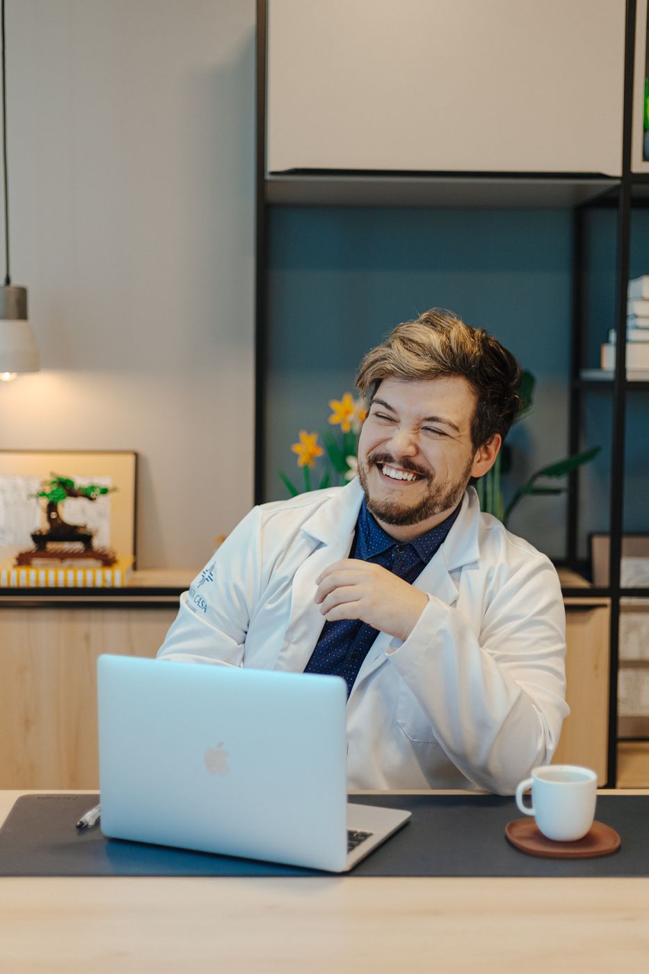 Dr. João Pedro sorrindo, de jaleco, em seu consultório